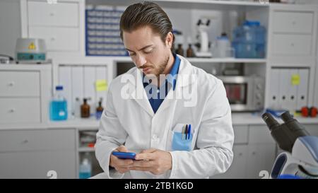 Young hispanic man scientist using smartphone at laboratory Stock Photo