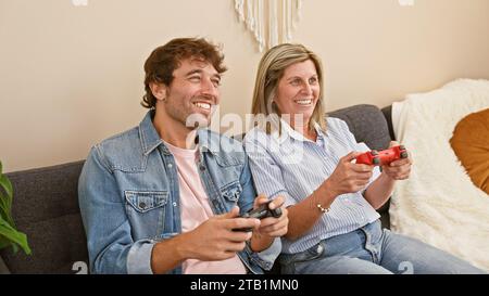 Mother and son sitting on sofa together playing video game at home Stock Photo