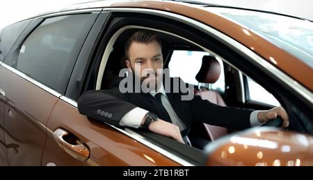 Close up portrait of handsome confident stylish bearded businessman while he driving his car. Modern luxury electric car Stock Photo