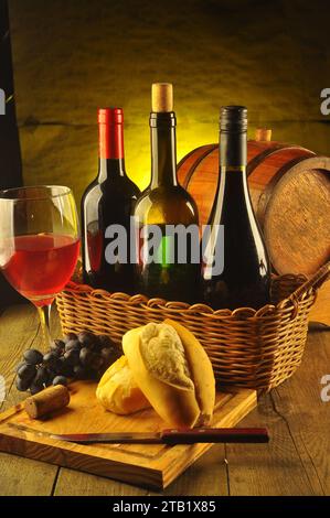 Still life with tree bottles of wine and glass .grape ,bread and knife on wodden board.over yellow gradient. Stock Photo