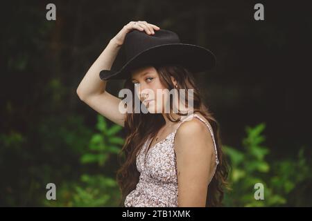 portrait of young girl tipping cowboy hat Stock Photo