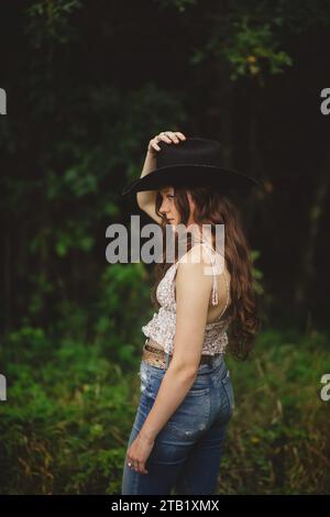 portrait of a girl with long hair and jeans wearing cowboy hat Stock Photo