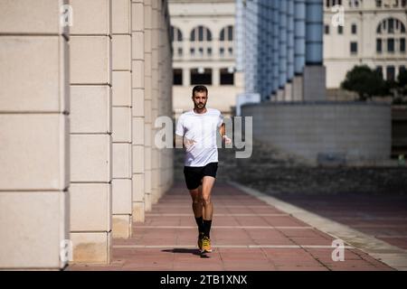 Fit young athletic man running outdoors training in a park. Stock Photo