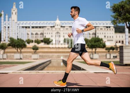 Side view of runner man training with a stadium in background. Stock Photo