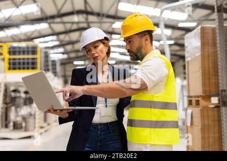 Female manager talking with foreman, checking production plan on notebook. Woman quality controller checking quality of products, talking with Stock Photo