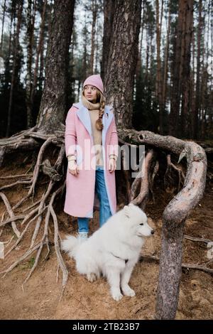 young girl walks with a white fluffy Samoyed dog in nature Stock Photo