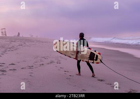 An older surfer walks on the beach with his surfboard on Cape Cod Stock ...