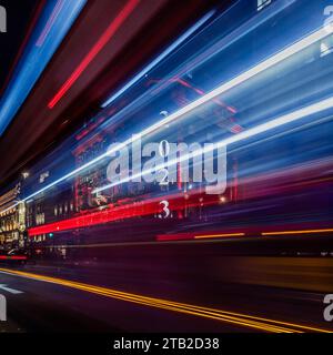 A long exposure of a red London bus passing by the advent calendar on the frontage of Fortnum & Mason in London during the festive period. Stock Photo