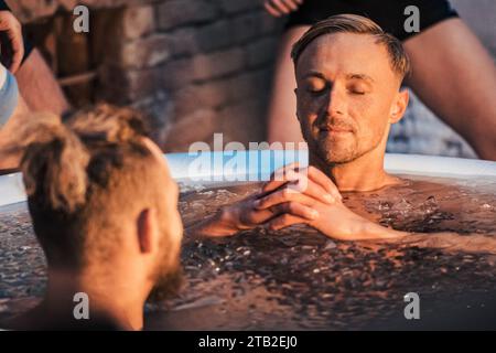 Handsome boy or man ice bathing in the cold water among ice cubes. Wim Hof Method, cold therapy, breathing techniques, yoga, meditation Stock Photo
