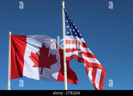 Die Flagge von Kanada links und die US-amerikanische Flagge nebeneindander. Blauer Himmel. Die Flagge von Kanada links und die US-amerikanische Flagge nebeneindander. Blauer Himmel. *** The flag of Canada on the left and the US American flag next to each other Blue sky The flag of Canada on the left and the US American flag next to each other Blue sky Credit: Imago/Alamy Live News Stock Photo