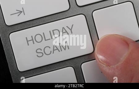 A man pressing a holiday scam button on a compter keyboard to report a fake holiday. Stock Photo