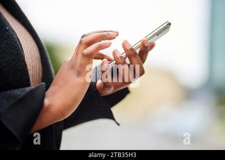 Cropped image of young Black woman hands in business wear holding cell phone  Stock Photo