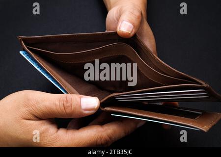 Man hand open an empty wallet isolated on black background. Stock Photo