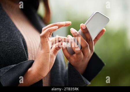 Cropped image of young Black woman hands in business wear holding cell phone  Stock Photo