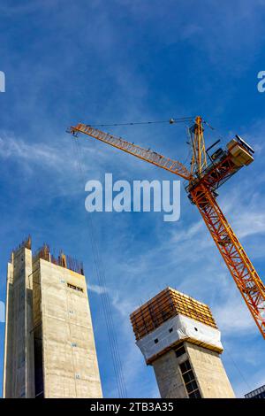 High rise buildings under construction with crane and blue sky in the background. Stock Photo