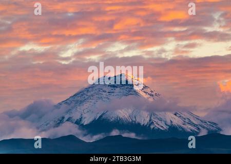 Cotopaxi volcano at sunset with clouds in blue and red tones seen from Quito, Ecuador Stock Photo