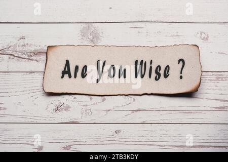 Motivational quote on burnt edge brown paper on wooden desk - Are you wise. Stock Photo
