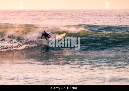 Surfing at Sunset. Young Man Riding Wave at Sunset. Outdoor Active Lifestyle. Stock Photo