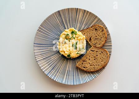 an image of freshly scrambled eggs served with brown bread toast. Stock Photo