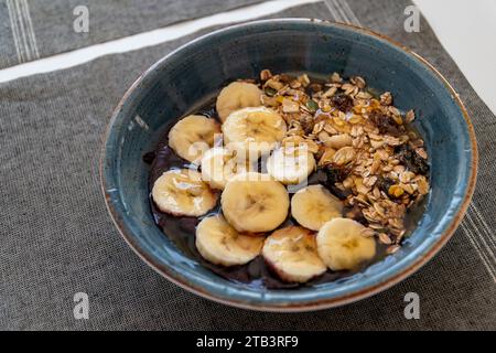 a bowl of healthy acai ice cream topped with banana oats and honey. Stock Photo