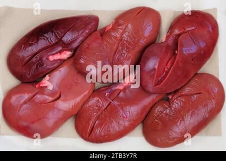 Raw pork kidneys in board on light background. Raw meat. Top view. Stock Photo