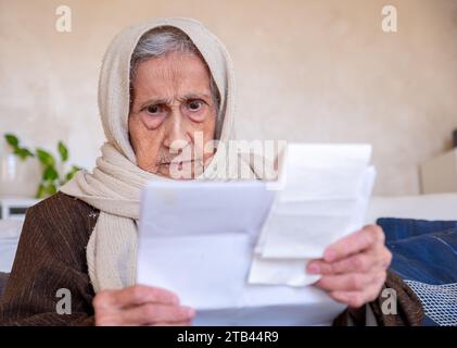 old lady holding receipt checking costs of living and house rent and her debts Stock Photo