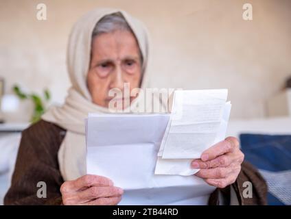 old lady holding receipt checking costs of living and house rent and her debts Stock Photo