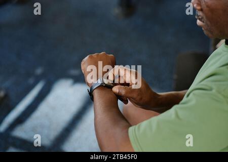 Medium closeup of unknown african american man pushing side buttons of his smartwatch, copy space Stock Photo