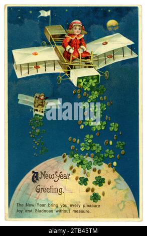 Original quaint Titanic era New Year's Eve greetings postcard of girl in red coat, flying a biplane (planes really did look like this then!) over the Earth, scattering 4-leaved lucky clovers from it, dated / posted Dec 24 1913 Stock Photo