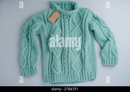 Turquoise sweater Knitted woolen with tag on a gray background, isolated Stock Photo