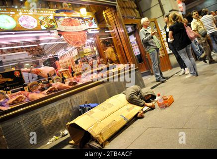 MADRID, SPAIN - MAY 2, 2010: Sleeping homeless man on a sidewalk near cafe in central Madrid. Stock Photo