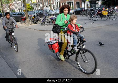 AMSTERDAM, NETHERLANDS - MAY 13, 2011: Woman with boy riding bicycle in historical part of Amsterdam. Stock Photo