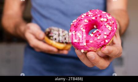 High angle view of chocolate donut with sprinkles in male hands. Stock Photo