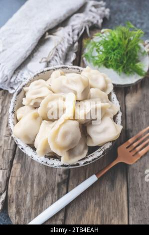 Handmade dumplings with greens in rough, handmade dishes. Close-up. Stock Photo