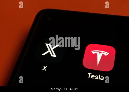X app and Tesla app icons seen on the corner of smartphone screen. Concept. Stafford, UK, December 2023 Stock Photo