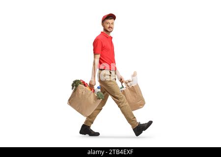 Full length shot of a delivery guy carrying bags with groceries and looking at camera isolated on white background Stock Photo