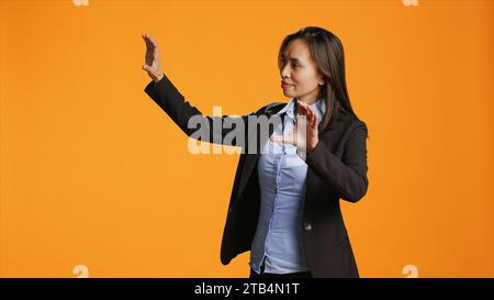 Office worker uses metaverse holographic image in studio, examining modern artificial intelligence reflection in front of camera. Businesswoman checks hologram icon projection. Stock Photo