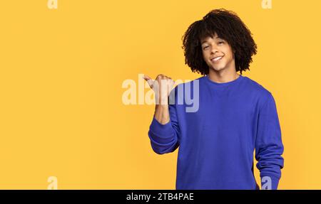 Handsome Black Guy Pointing Aside At Copy Space With Hand Stock Photo
