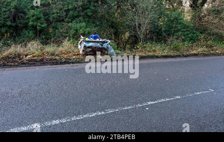 Environmental pollution in the form of a very large, commercial sized, bag of waste fly-tipped beside a busy road in the countryside Stock Photo