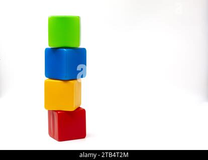 Multicolored plastic cubes for children's games. Yellow and blue with green cubes stands on top of red. The cubes are turreted. One on one. Stock Photo
