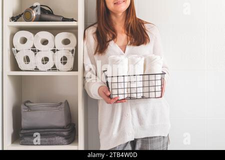 Woman's hands neatly putting or displaying a clean rolled up white towels made from organic cotton. Stock Photo