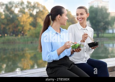 Business people eating from lunch boxes outdoors. Space for text Stock Photo