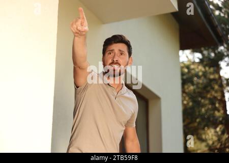 Pointing Near Angry man pointing near house. Annoying neighbour Stock Photo - Alamy