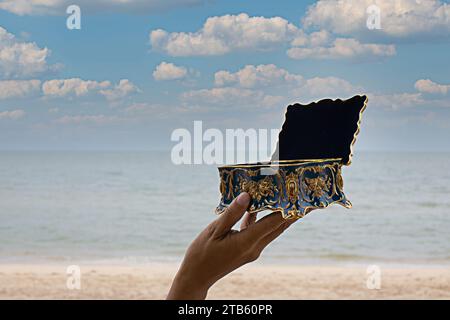 a treasure chest in a woman's hand sea background Stock Photo