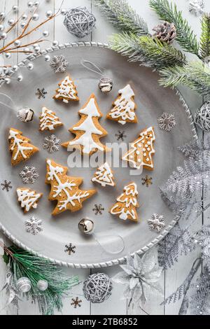 A metal tray of tree gingerbread cookies surrounded by glitter decorations. Stock Photo