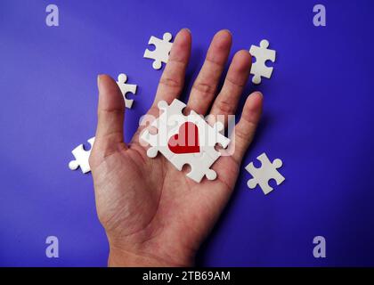 A hand with puzzle pieces that make up a heart. The concept of a complementary relationship, solving love problems together. Stock Photo