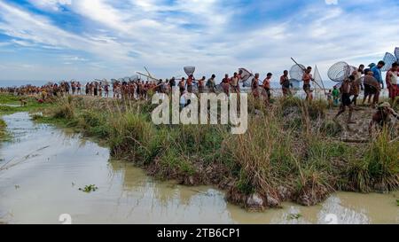 Rural people armed with Bamboo fish traps and nets take part in celebrating a 200-year winter fishing festival at the jofra beel of gasbari union of Kanaighat upazila of Sylhet, Bangladesh. Stock Photo
