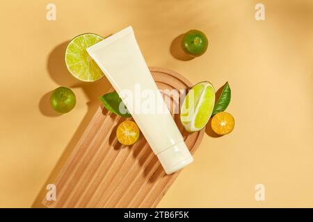 An unlabeled cosmetic tube is placed on a dome-shaped platform, surrounded by lemons and kumquats. These are two fruits rich in vitamin C that are goo Stock Photo