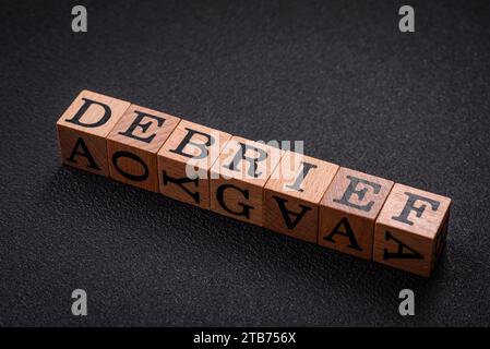 The inscription debrief in wooden cubes on a dark concrete background. Can be used as part of your composition Stock Photo