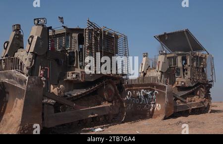 Israeli D9 armored military bulldozers stand in a field near the border with the Gaza Strip amid continuing battles between Israel and the militant group Hamas after a week long ceasefire ended on December 3, 2023 in Gaza border, Israel. Israel steps up military operations in Gaza after a sustained truce between Hamas and Israel did not hold further than a week despite diplomatic talks and captives released. Stock Photo